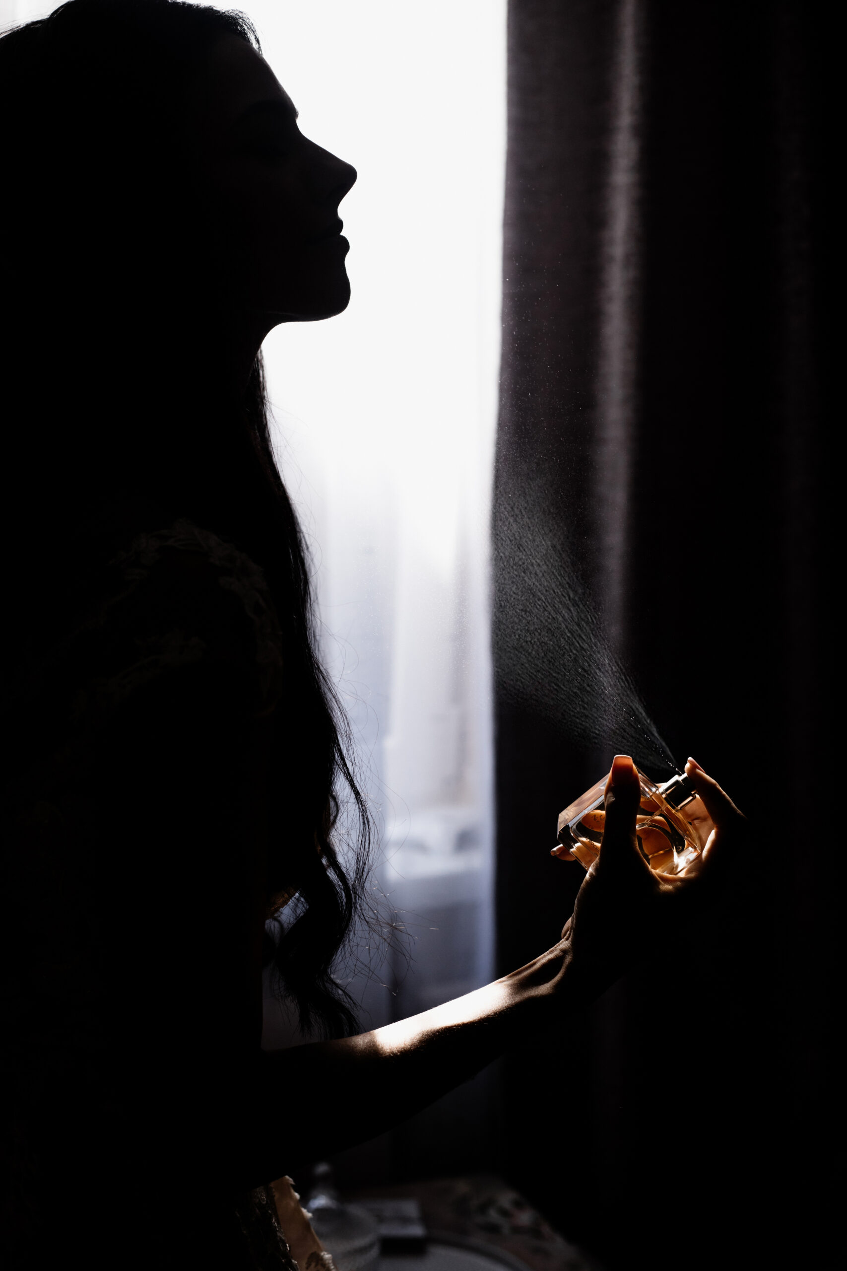 HomE silhouette of young girl who is perfuming in front of window in
